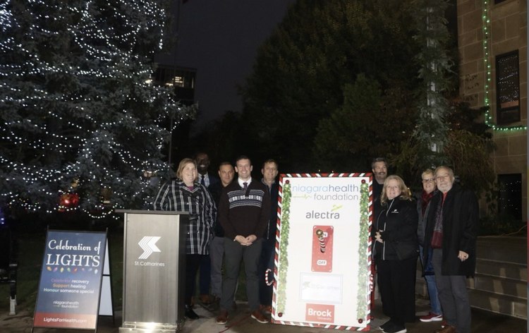 Group gathered by the lit tree and Celebration of Lights sign outside St. Catharines City Hall